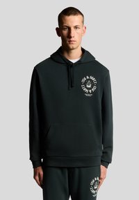 Felpa nera con cappuccio in materiale morbido, dotata di una tasca frontale. Il design include una stampa grafica bianca sul lato sinistro del petto e pantaloni coordinati.