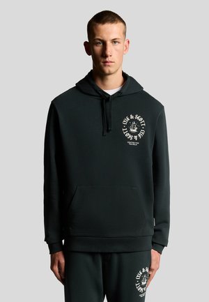 Sort hættetrøje i blødt materiale med en frontlomme. Designet inkluderer hvid grafisk print på venstre bryst og matchende sweatpants.