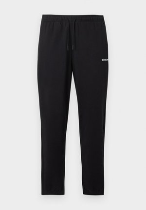 Czarne wąskie spodnie dresowe z elastycznym pasem, sznurkiem do ściągania, mankietami przy kostkach i małym białym logo na prawej udzie.