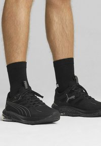 Czarne sportowe sneakersy z siateczkowymi panelami, teksturowanymi gumowymi podeszwami i sznurowanym designem. Posiadają subtelne logo z boku i na języku.