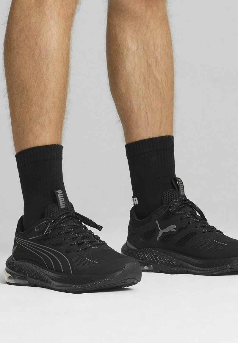Czarne sportowe sneakersy z siateczkowymi panelami, teksturowanymi gumowymi podeszwami i sznurowanym designem. Posiadają subtelne logo z boku i na języku.