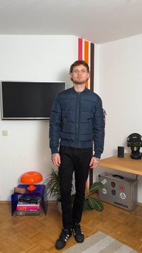 Μπλε φουσκωτό μπουφάν με φερμουάρ μπροστά, ριγέ μανίκια και οριζόντια ραφή. Σα ντύθηκε με μαύρο παντελόνι και αθλητικά παπούτσια Adidas.