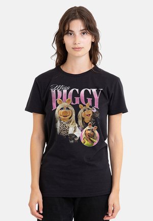 Young woman wearing a black T-shirt featuring three images of Miss Piggy from The Muppets with pink text above.