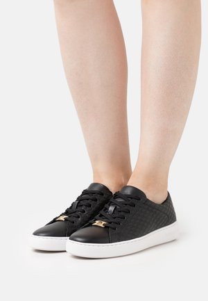 Baskets noires en cuir texturé et lisse, bout rond, fermeture à lacets, semelle blanche et accents dorés sur la languette.