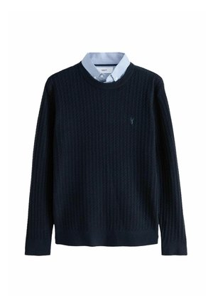 Suéter de punto acanalado azul marino con cuello redondo y mangas largas, superpuesto a una camisa de cuello azul claro. Logo sutil en el pecho.