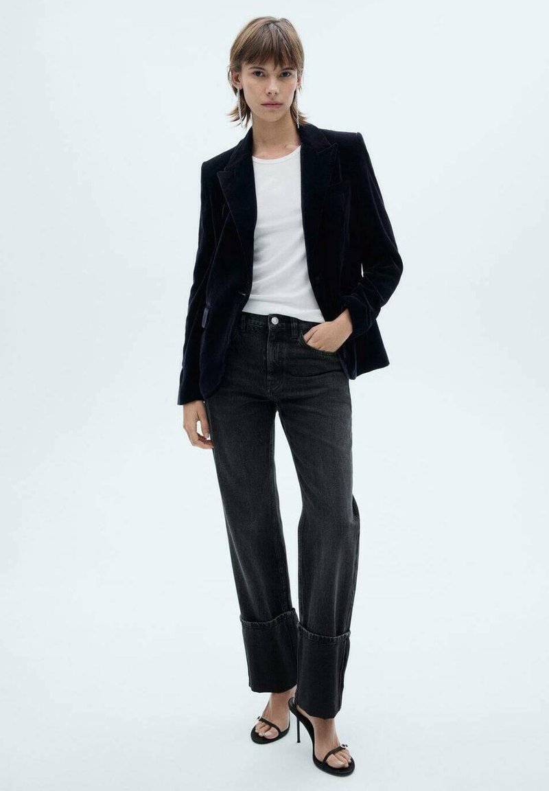 Satin sort blazer, hvid skjorte, mørke denim jeans med opsmøg, og sorte stiletter; minimalistisk design og rene linjer.