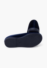 Zapatos de terciopelo azul marino con punta redonda y tacón bajo. Suela de goma texturizada con ranuras verticales para mayor agarre. Diseño limpio y minimalista.