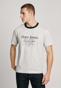Pilkos spalvos trumpomis rankovėmis marškinėliai su tamsiai mėlynu raštuotu apykaklės kraštu. Su "Pepe Jeans" prekinio ženklo logotipu ir tekstu, atspausdintu tamsiai mėlyna spalva. Minkšta tekstūra, laisvas siluetas.
