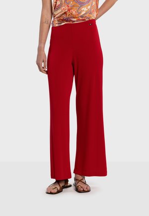 Røde bukser med vide ben lavet af blødt stof med en glat tekstur, med høj talje og en diskret logoaccents. Bruges med flade sandaler.