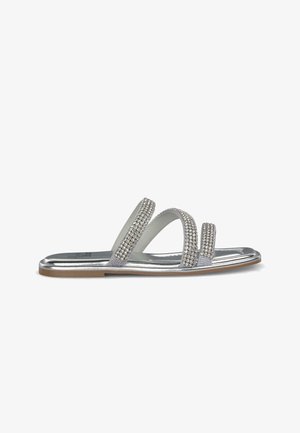 Srebrne sandały z trzema szerokimi paskami ozdobionymi przezroczystymi cyrkoniami, metaliczną podeszwą i teksturowaną wkładką.