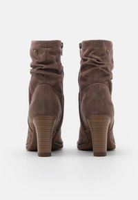 Bottines en daim marron à design décontracté, fermeture éclair et talon empilé ; avec des accents dorés et une semelle texturée.