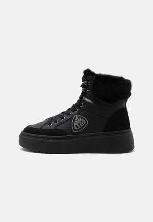 Sneaker nera alta con suola spessa, chiusura frontale con lacci, colletto in pelliccia e toppa con logo a forma di scudo sul lato.