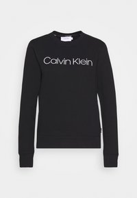 Sudadera negra de manga larga, con cuello redondo y el logotipo "Calvin Klein" en blanco en el pecho. Textura de tela suave; puños y dobladillo acanalados.