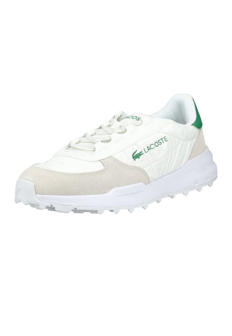 Sneaker Lacoste bianco e beige con logo verde, chiusura con lacci e suola testurizzata, inclinata per mostrare il lato esterno e la parte anteriore.
