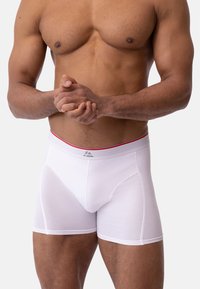 Calzoncillos bóxer blancos hechos de tela suave, con una cintura gris con detalles en rojo y un ajuste ceñido, diseñados para brindar comodidad y soporte.