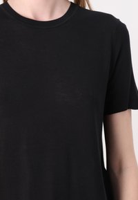 Svart T-shirt i mjukt tyg, med rund halsringning och korta ärmar med ribbade detaljer. Enkel design i en solfärg.