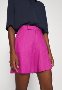 Fuchsia linnebyxor med en åtsittande midja, bälteshällor och dubbla framfickor. Tyget har en strukturerad yta.