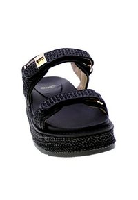 Sandali platform neri con cinturini intrecciati, dettagli in tono oro e suola texturizzata. Presentano una soletta imbottita per il comfort.