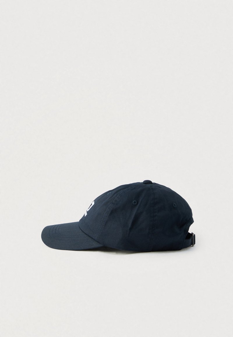Gorra de algodón azul marino con una visera curva, correa ajustable en la parte trasera y detalle de logo blanco en el frente. Textura suave y diseño informal.