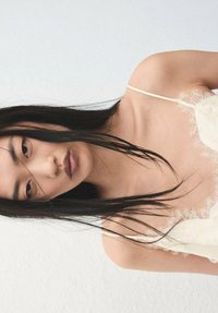 Camisola de encaje en color crema claro con tirantes finos, que presenta un delicado patrón floral en los bordes y una textura de tela suave y translúcida.