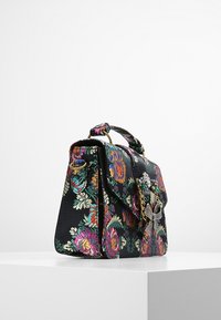 Torebka w kwiatowy wzór z czarnego materiału, z ozdobnym zapięciem, złotymi akcentami i sztywną formą z rączką u góry.