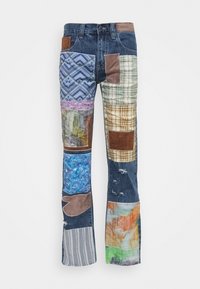 Jeans de mezclilla tipo patchwork con diversas texturas y colores de tela, incluyendo azul, marrón, cuadros y patrones abstractos, con un diseño acampanado.