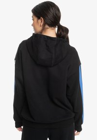 Sudadera negra con capucha amplia, corte relajado y detalles en azul en las mangas. Fabricada con material suave y acabado texturizado.