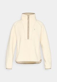 Κρέμ φλις πουλόβερ με φερμουάρ μέχρι τη μέση μπροστά, αντίθετες μπεζ λεπτομέρειες, γιακά που στέκεται και ραμμένα σχέδια. Μαλακό, υφασμάτινο με υφή.