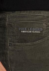 Maslinaste zelene pantalone od kordura imaju stražnji džep s izvezenim "PME Legend" i "American Classic" u mornarskom plavom i bijelom koncu.