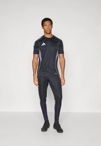 Mustad sportlik särk ja püksid, millel on lilla ja roheline aktsent, lühikesed varrukad ja kitsas lõige, valmistatud kerge ja elastse materjali.