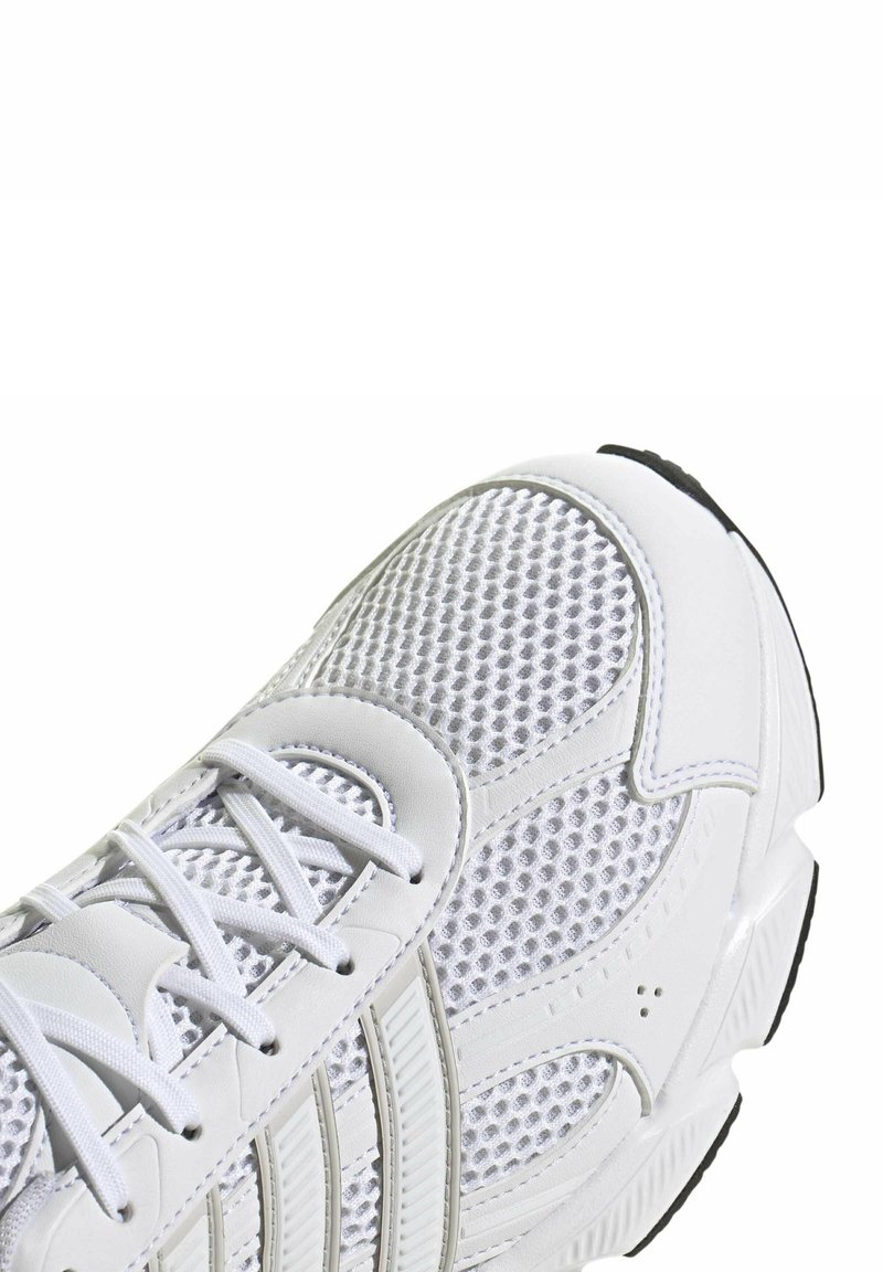 White athletic shoe featuring a breathable mesh upper, lace closure, textured accents, and a black rubber outsole.