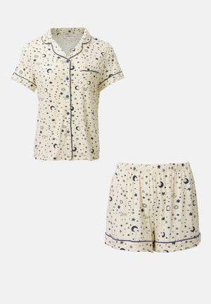 Lyhyt pyjama-setti kermavärisestä kankaasta, jossa on laivastonsinisiä tähtiä ja kuu kuvioita. Sisältää nappikauluspaitan lyhyillä hihoilla ja yhdisteeseen sopivat elastiset vyötäröhousut.
