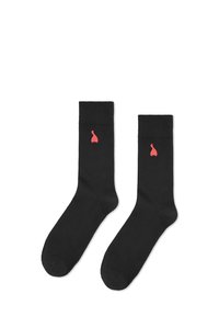 Czarne bawełniane skarpetki z dopasowanym mankietem na kostkę, z małym czerwonym logo w kształcie kropli po zewnętrznej stronie. Gładka tekstura, standardowa długość.
