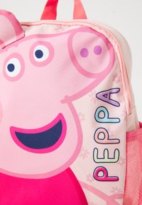 Mochila infantil rosa com um design de porquinho de desenho animado, com uma textura de tecido suave, alças ajustáveis e o nome "Peppa" em letras coloridas.
