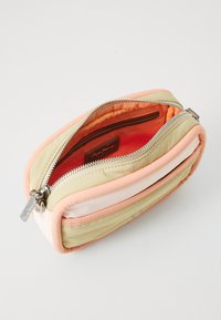 Rektangulær pouch i dæmpede pastelfarver med en tekstureret stofflade, der har en sølvfarvet lynlås og en lys orange foring.