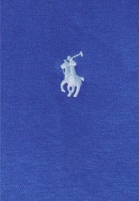 Kungslila bomullstyg med en texturerad yta, med en liten vit broderad polo spelare-logotyp.