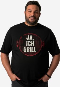 Black T-shirt featuring a round, distressed graphic with red accents and the words "JA, ICH GRILL" in bold white font. Casual fit.