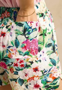 Gėlėti šortai turi daugiapalvį raštą su didelėmis rožinėmis, raudonomis ir žaliomis gėlėmis. Audinys yra lengvas, su elastine liemene ir kišenėle.