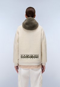 Κρέμας χρώματος φλις μπουφάν με ελαιοπράσινη κουκούλα, ριχτές μανσέτες και στρίφωμα; διαθέτει το λογότυπο "NAPAPURI geographic" στην πλάτη.