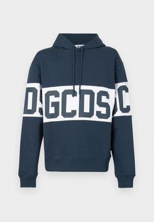 Tumesinise kapuutsiga sviiter, millel on valge horisontaalne triip rinnal ja kätes, triibul on suured tumesinised tähed "GCDS".