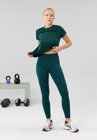 Zöld sportfelső és leggings sima anyagból. A felső rövid ujjú, míg a leggings magas derékú.