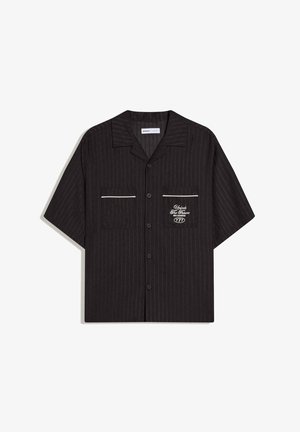 Cămașă neagră cu mâneci scurte și nasturi, cu dungi subțiri discrete, două buzunare frontale cu margini albe și text alb pe buzunarul din dreapta.