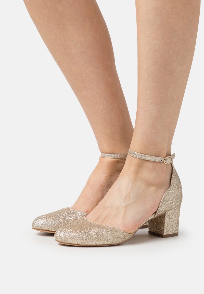 Glittering gold block-heeled shoes with an ankle strap and rounded toe. Sparkling texture and smooth surface, providing a secure fit.