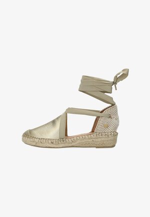 Gouden leren espadrille met beige stoffen bandjes, gevlochten juten zool en een geweven textuur bij de hiel. Elegant en open ontwerp.