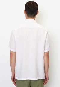 Korte mouwen, wit linnen shirt met een subtiele textuur, kraag en afgeronde zoom, van achteren getoond met gebroken witte accenten op de mouwen.