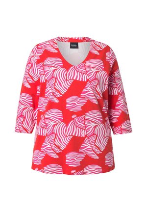 Punainen v-kaula-aukkoinen paita, jossa on vaaleanpunainen ja valkoinen abstrakti seepra-raidallinen kuvio ja puolipitkät hihat.
