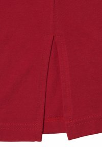 Rode katoenen t-shirt met een subtiele split aan de onderzoom, met nette stikseldetails. Zachte textuur verhoogt het comfort.