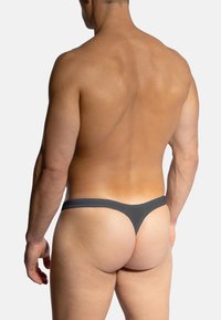 Graue Stringunterwäsche aus glattem Material, mit minimaler Bedeckung und niedrigem Bund, von hinten gezeigt. Hautton sichtbar.