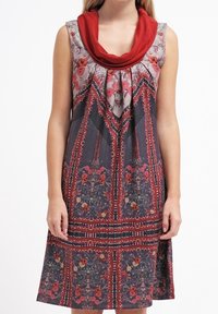 Mouwloze jurk met een rode col, met een donker bloemenpatroon met rode en crèmekleurige accenten, en een uitlopende rokontwerp.