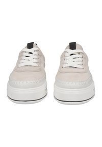 Beige suède sneakers met witte veters en een zwarte hieltab. Dikke witte zool met een zwarte accentlijn. Geweven details op het bovenwerk.